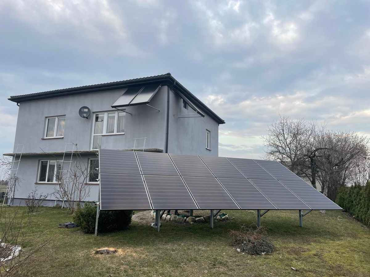 Naziemna instalacja fotowoltaiczna obok piętrowego domu